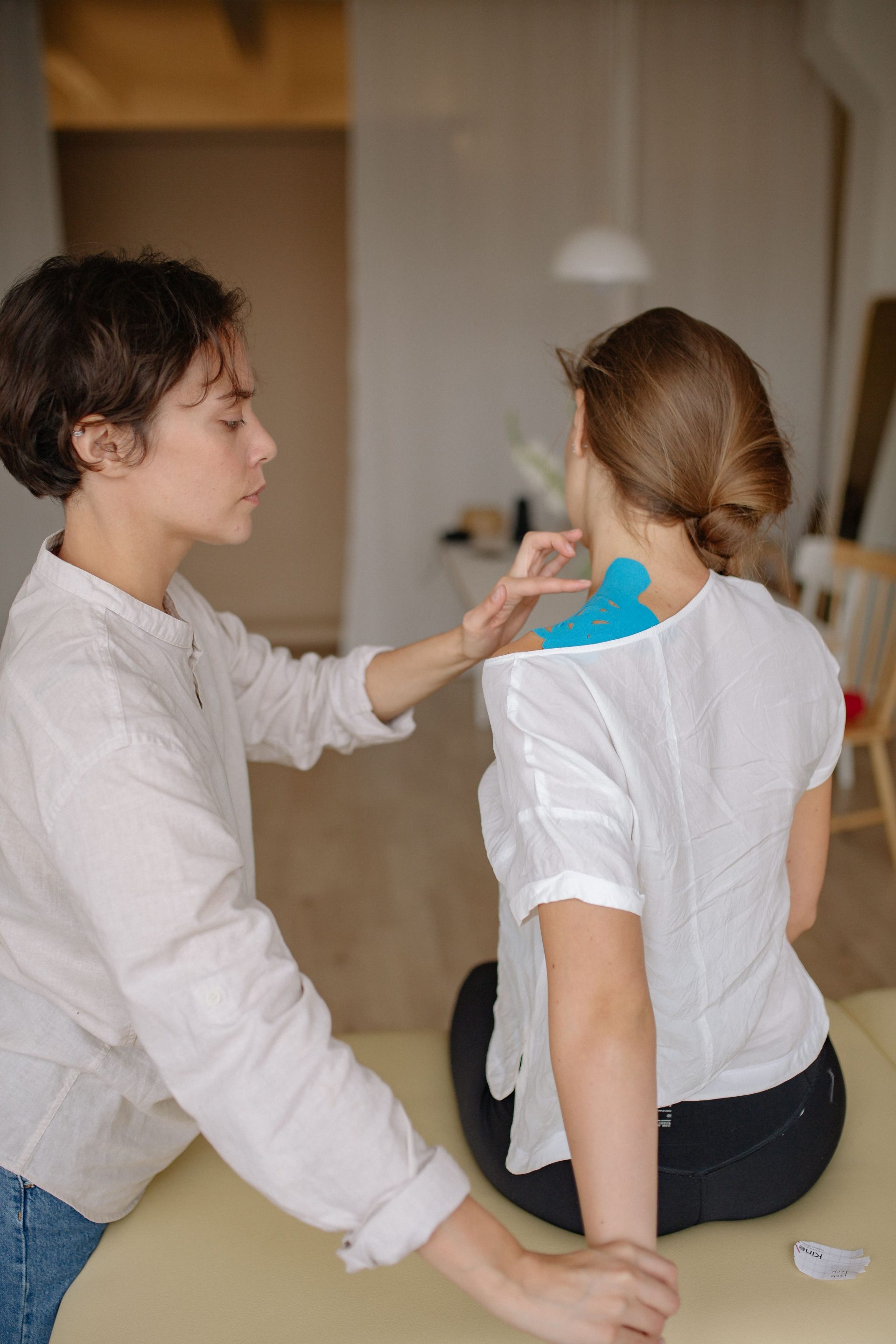 Ein Chiropraktiker bringt während einer Schulterbehandlung in Innenräumen Therapietape an.